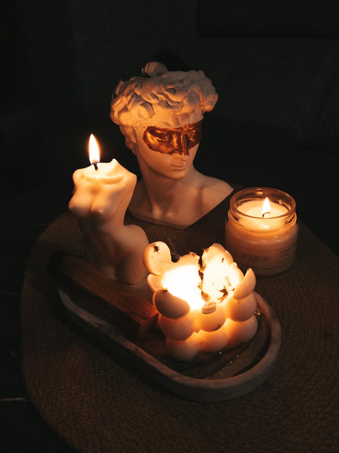 Artistic candle display with sculptural wax designs and a classical bust.