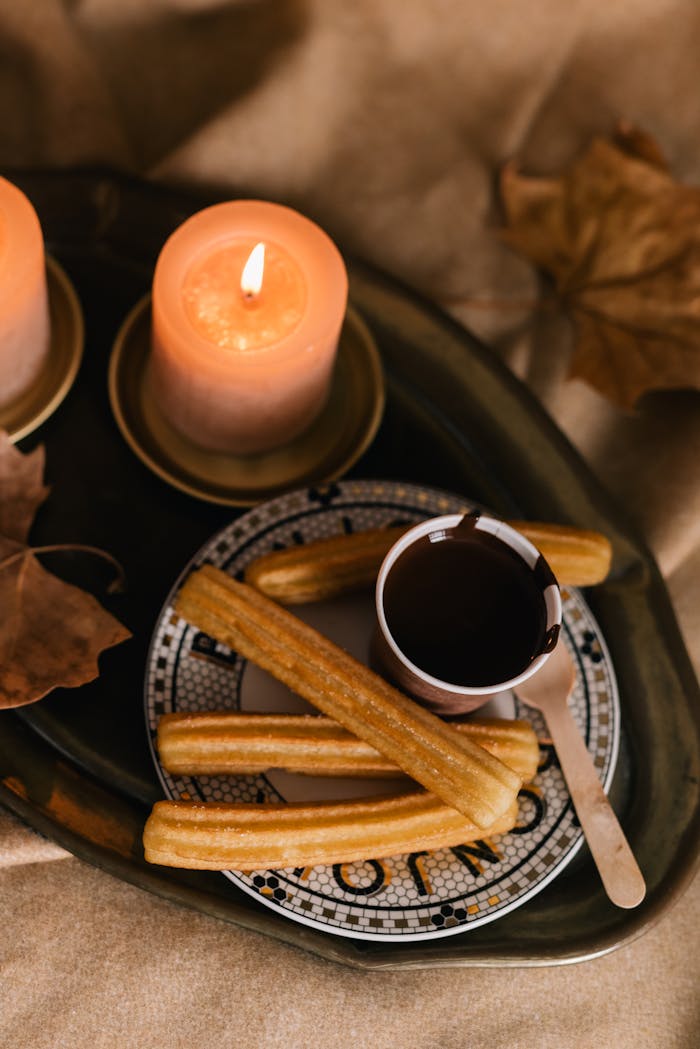 A warm display of churros with chocolate beside glowing candles, perfect for cozy evenings.